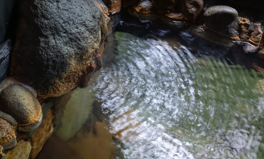 岩に囲まれた湯船に広がる、湯の波紋